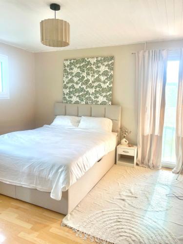 a bedroom with a white bed and a window at Comfortable apartment a stone's throw from Nyon in Duillier