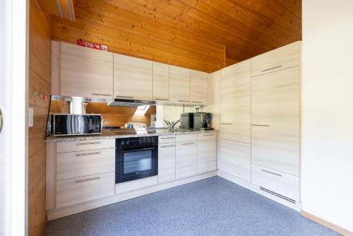a kitchen with white cabinets and a wooden ceiling at Zentrale Ferieneohnung in Grindelwald in Grindelwald