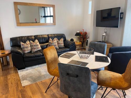 a living room with a black leather couch and a table at Auld Leigh-Lann Apartments in Anstruther