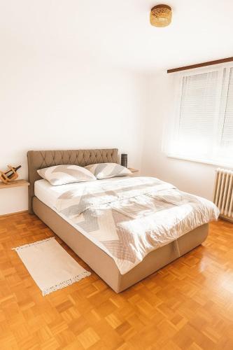 - un lit blanc dans une chambre dotée de parquet dans l'établissement Apartman Centar Banja Luka, à Banja Luka