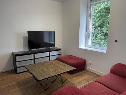 a living room with a tv and a couch and a table at Le ONZE in Longwy