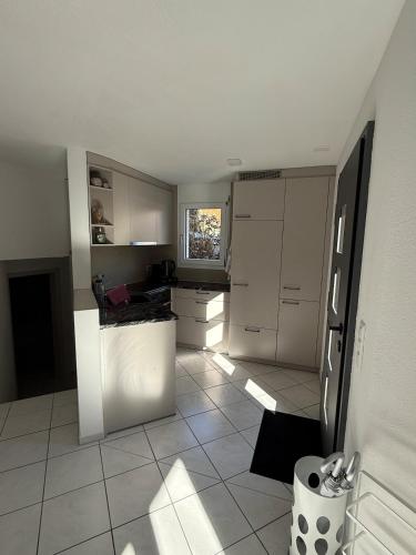 a kitchen with white cabinets and a tile floor at Terrassenwohnung mit Parkplatz in Wangen
