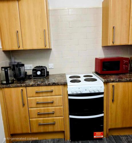 a kitchen with a stove and a red microwave at Oge's House in Bradford
