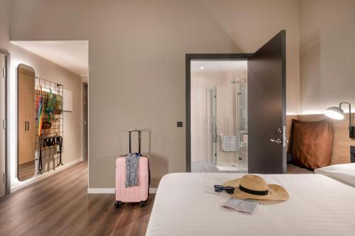 a bedroom with a bed with a hat and a suitcase at Moxy Verona in Verona