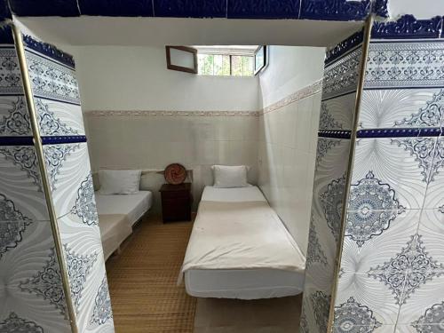 a room with two beds in a room with a window at Miramar GuestHouse in Taghazout