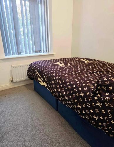 a bedroom with a bed with a comforter and a window at Oge's House in Bradford