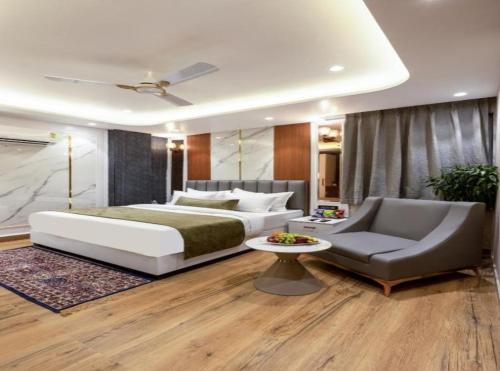 a bedroom with a bed and a couch and a table at Hotel Rosewood Suites Near Delhi Airport in New Delhi