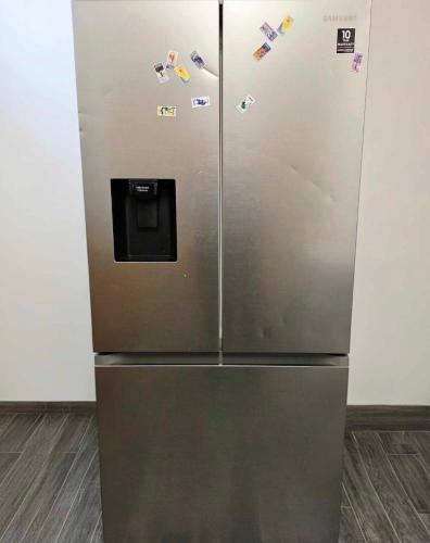 a stainless steel refrigerator with magnets on it at Oge's House in Bradford
