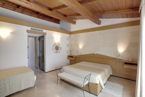 a bedroom with two beds in a room with wooden ceilings at Masseria Stali, The Originals Relais in Caprarica di Lecce