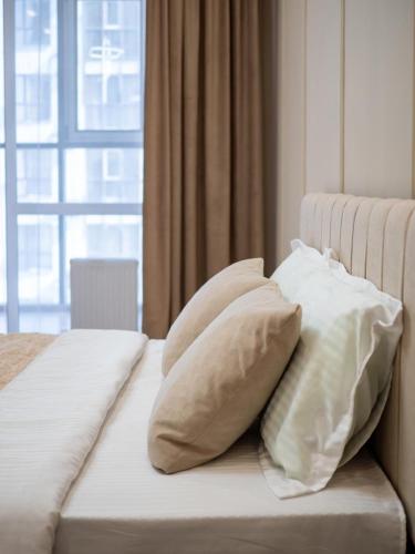 a bed with white pillows on it with a window at Комфортная евродвушка у проспекта Абая, рядом с метро in Almaty
