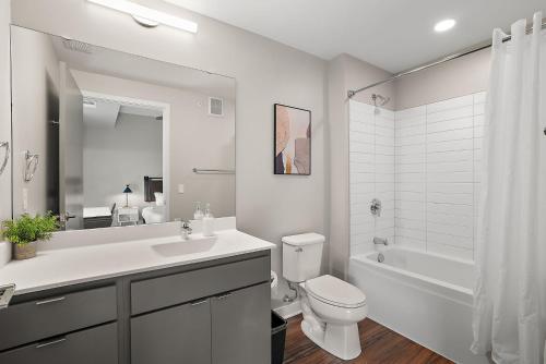 een badkamer met een wastafel, een toilet en een bad bij CozySuites Marquee in Minneapolis