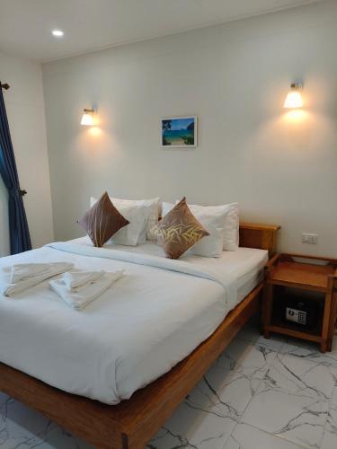 a bedroom with a large bed with white sheets and pillows at MookSkyDawBungalow in Trang