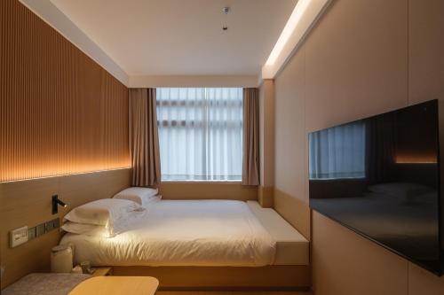 a small room with two beds and a flat screen tv at 船长五号青年酒店-上海中山公园江苏路地铁站店 in Shanghai