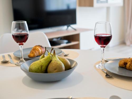 a table with two glasses of wine and a bowl of pears at Apartament Palisadowa by Enklawa in Wałbrzych