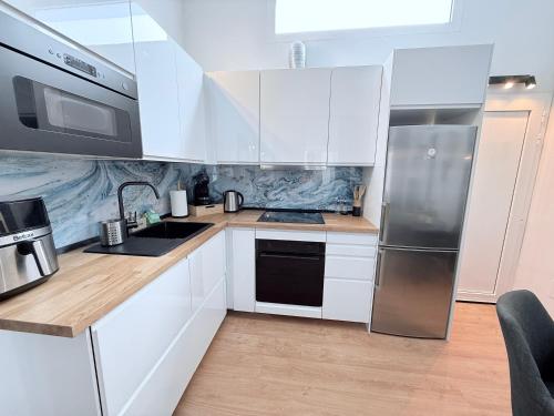 a kitchen with white cabinets and a stainless steel refrigerator at HDFM Collection - Bungalow Playa del Inglés in Playa del Ingles