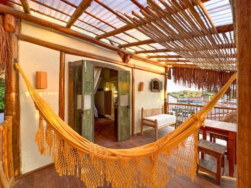 a hammock on a house with a balcony at Casa Felina in Ilha de Boipeba