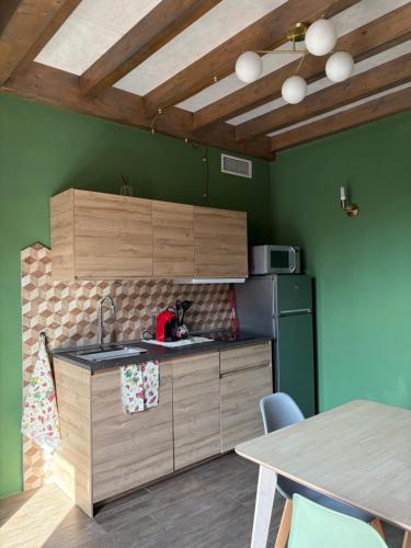 a kitchen with green walls and wooden cabinets and a table at Sala dell Estate Guest House in Secchia