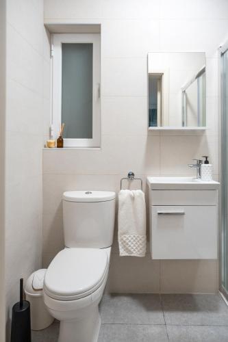 a white bathroom with a toilet and a sink at Ocean Blue Onyx in Marsaskala