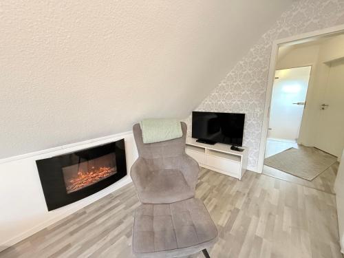 a living room with a chair and a fireplace at Ferienwohnung Haus Moorblick Garten mit Terrasse Netflix E-Kamin Thermomix in Wiesmoor