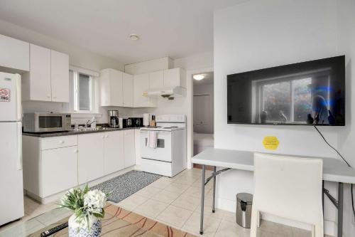 eine Küche mit weißen Geräten sowie einem Tisch und Stühlen in der Unterkunft Luxury 1-Bedroom Suite in Vancouver in Vancouver