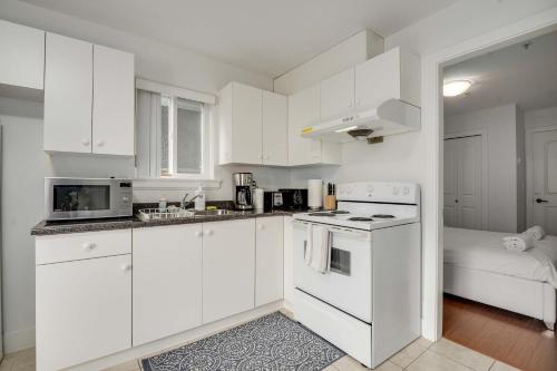 eine Küche mit weißen Schränken und einem Herd mit Backofen in der Unterkunft Luxury 1-Bedroom Suite in Vancouver in Vancouver