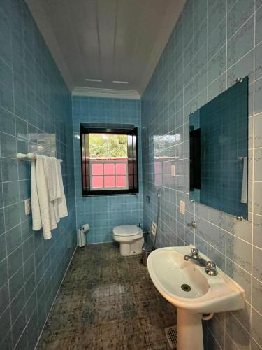 a blue tiled bathroom with a toilet and a sink at Suites Matriz Centro Histórico in Paraty