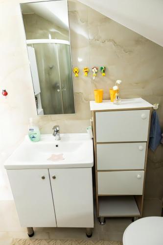 a white bathroom with a sink and a mirror at Sanlej Apartman in Tuzla