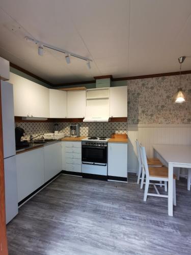 eine Küche mit weißen Schränken, einem Tisch, einem Tisch und Stühlen in der Unterkunft FW Järeda in Järnforsen