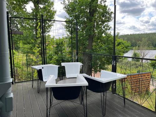 a balcony with two tables and chairs and a view of a lake at Stodoła i Stolarnia in Gałęzów