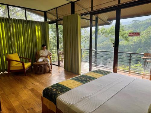 a person sitting in a chair in a room with a bed at Aqua Dunhinda Nature Retreat in Kandy