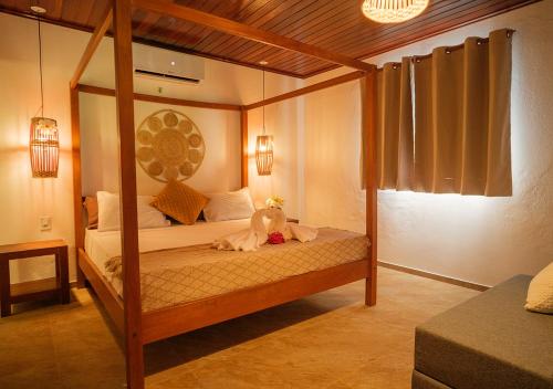 a bedroom with a canopy bed with a stuffed animal on it at Kite Oasis Parajuru Villa Palmeira in Parajuru