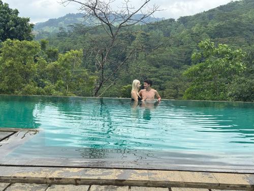 a man and a woman sitting in a swimming pool at Aqua Dunhinda Nature Retreat in Kandy