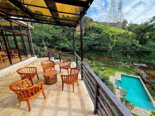 a deck with chairs and a table and a swimming pool at Aqua Dunhinda Nature Retreat in Kandy