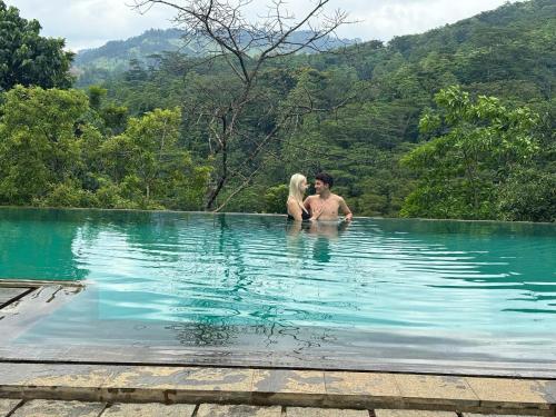 a man and a woman sitting in a swimming pool at Aqua Dunhinda Nature Retreat in Kandy