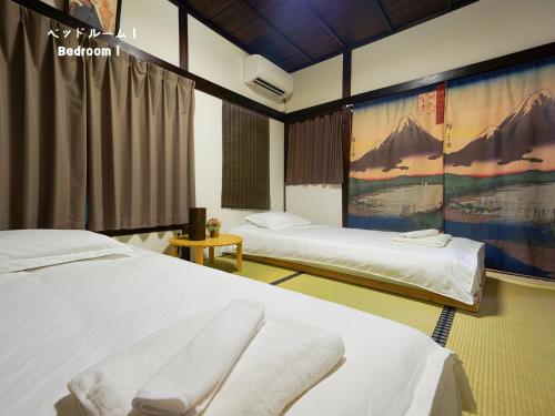 a room with two beds and a painting on the wall at 7時IN19時OUT # 池袋王子赤羽駅無料送迎 # テラスハウス # 駅近10分 # 上野駅電車12分 # 最大7名 # 7 00 IN19 00 OUT # Free pick-up at Ikebukuro, Oji, and Akabane Stations # Terrace House # 10 min to station # 12 min to Ueno # Max 7 in Tokyo