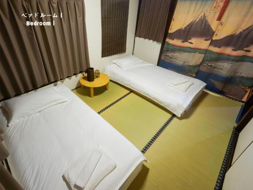 a room with two beds and a table in it at 7時IN19時OUT # 池袋王子赤羽駅無料送迎 # テラスハウス # 駅近10分 # 上野駅電車12分 # 最大7名 # 7 00 IN19 00 OUT # Free pick-up at Ikebukuro, Oji, and Akabane Stations # Terrace House # 10 min to station # 12 min to Ueno # Max 7 in Tokyo