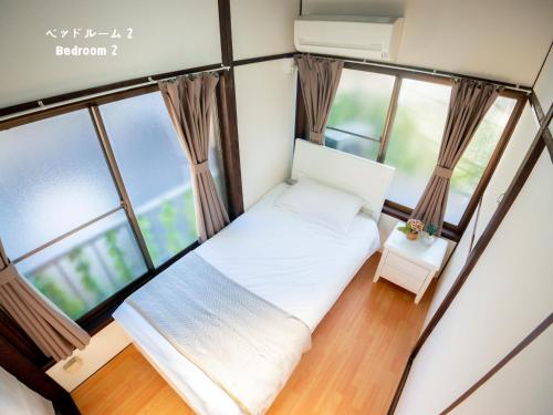 a small bed in a room with windows at 7時IN19時OUT # 池袋王子赤羽駅無料送迎 # テラスハウス # 駅近10分 # 上野駅電車12分 # 最大7名 # 7 00 IN19 00 OUT # Free pick-up at Ikebukuro, Oji, and Akabane Stations # Terrace House # 10 min to station # 12 min to Ueno # Max 7 in Tokyo
