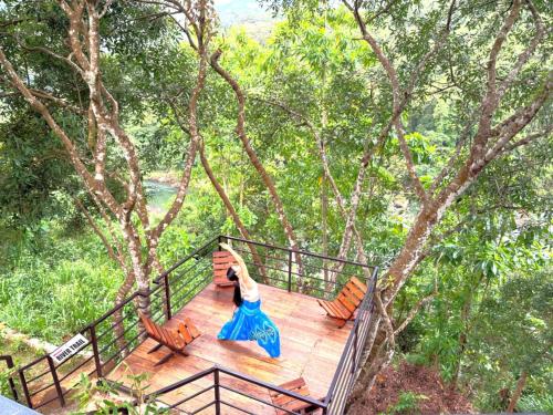 a woman standing on top of a wooden deck at Aqua Dunhinda Nature Retreat in Kandy