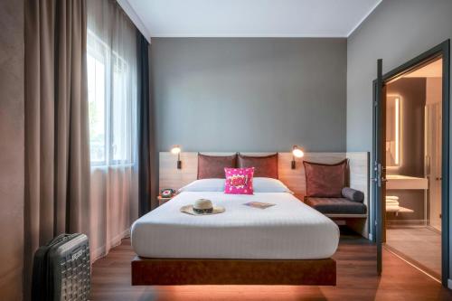 a bedroom with a large white bed and a chair at Moxy Verona in Verona