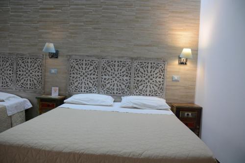 a bedroom with a large white bed with two tables at Syrakosia a Ortigia in Syracuse