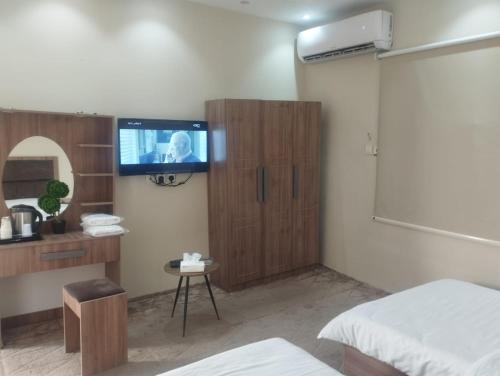 1 dormitorio con TV en la pared en Marasi, en Al Ula