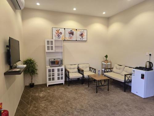 a waiting room with a couch and chairs and a tv at Marasi in AlUla