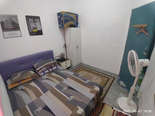 a bedroom with a bed and a fan at Sri Nawa Homestay in Pokok Sena