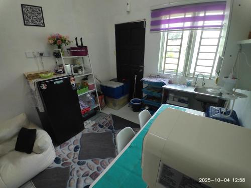a living room with a table and a kitchen at Sri Nawa Homestay in Pokok Sena