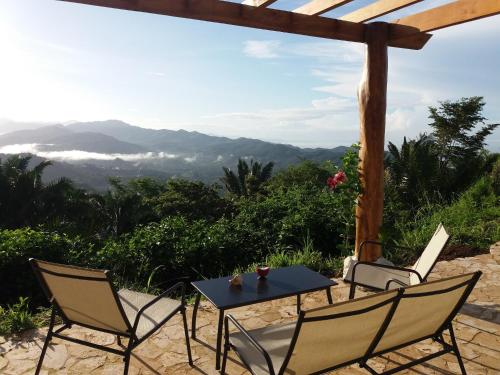 a table and chairs on a patio with a view of mountains at Hotel Peace & Lodge in Sámara