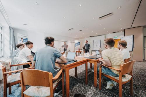 a group of men sitting at a table with laptops at Hotel Graf Bentinck in Dangast
