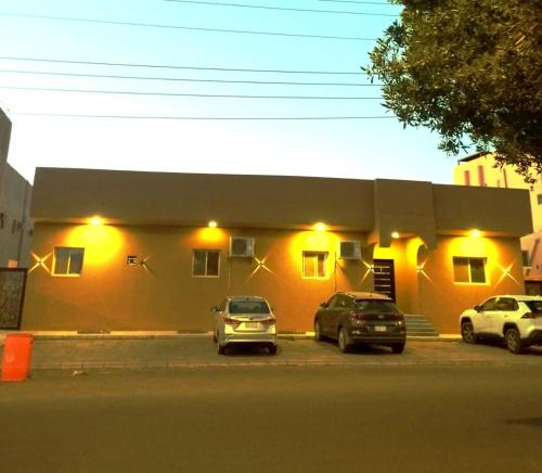 dos coches estacionados frente a un edificio con luces en Marasi, en Al Ula