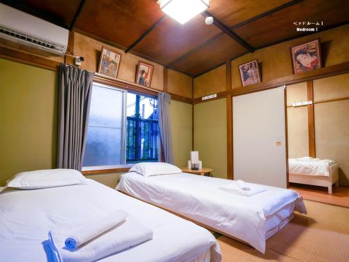 two beds in a room with a window and two bedsvisor at 7時IN19時OUT # 池袋王子赤羽駅無料送迎 # 上野駅14分 # 日暮里駅10分 # 一棟貸切 # 最大7名 A # 7 00 IN19 00 OUT # Free pick up Ikebukuro Oji and Akabane Stations # 14 min to Ueno # 10 min to Nippori # Whole house rental # Max 7 # A in Tokyo