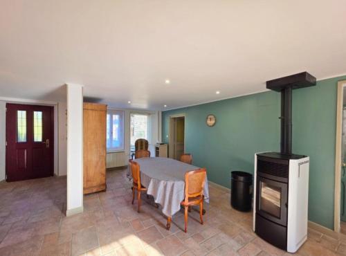a dining room with a table and a stove at Chez Marguerite et Lucienne in Bussière-Dunoise