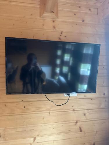 a television on a wall with a man taking a picture at DOMKI JANOSIK - Janosik Premium in Łopuszna